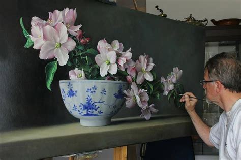 A Man Is Painting Flowers In A Blue And White Vase