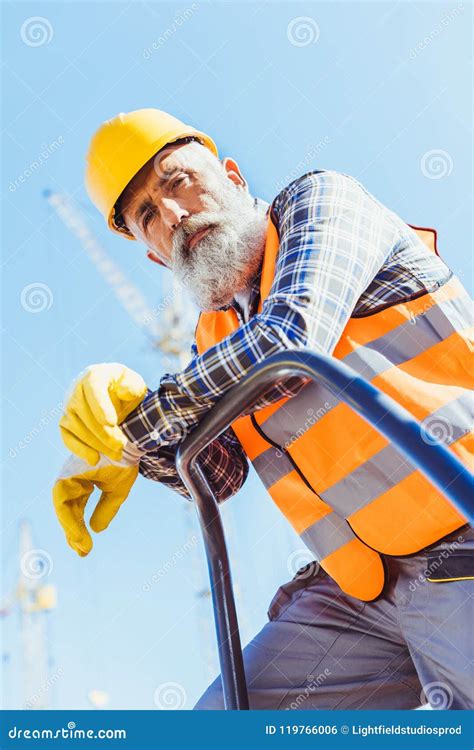 Bearded Construction Worker In Reflective Vest And Hardhat Leaning On