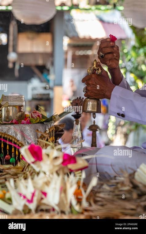 Balinese Hindu Priest Pemangku Dressed In White Holding A Bell