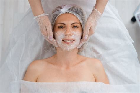 Top View Of Smiling Female Client Whose Beautician Makes Face Mask