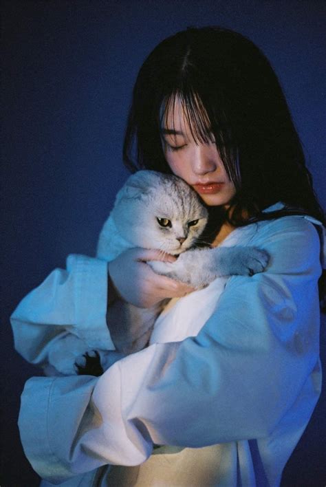 A Woman Holding A Cat In Her Arms While Wearing A White Shirt And Blue
