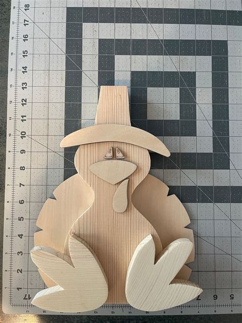 A Wooden Cutout Of A Turkey With A Hat On Its Head Sitting Next To A Ruler