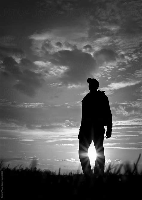 Silhouette Of Man Standing In A Field Against Sunlight By Stocksy