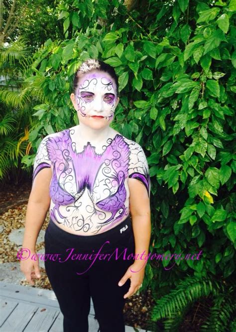 A Woman With Her Face Painted In Purple And White Standing On A Wooden