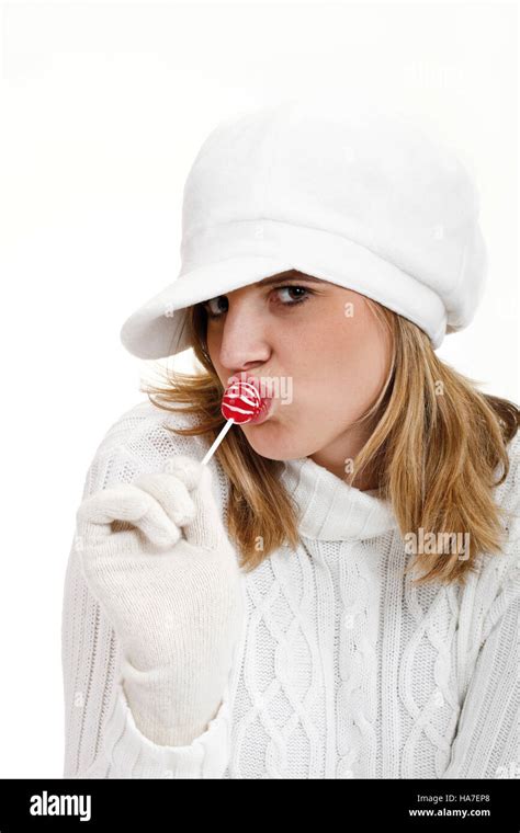 Young Woman In A White Turtleneck Sweater With Woolen Hat Sucking A