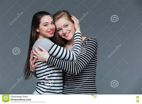 Dos Mujeres Jovenes Atractivas Sonrientes Que Se Colocan Y Que Abrazan Imagen De Archivo