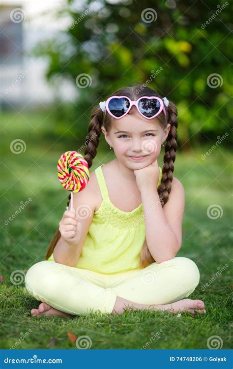 Милая маленькая девочка с большим красочным леденцом на палочке