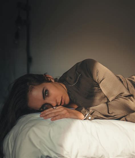 yatakta yatan kahverengi uzun kollu gömlekli kadın · Ücretsiz stok fotoğraf