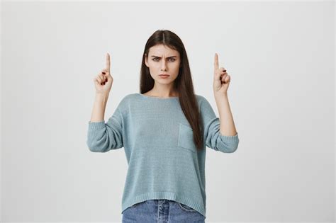 free photo skeptical angry woman pointing fingers up squinting upset