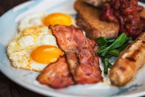 Typial Breakfast With Eggs Bacon And Sausage On Plate Stock Photo