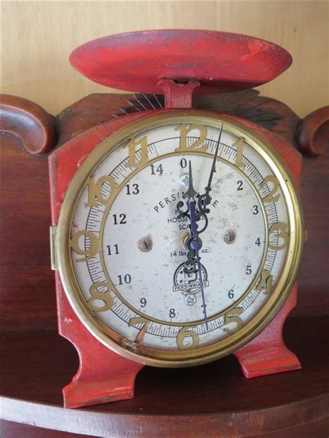 An Old Red Clock Sitting On Top Of A Wooden Table