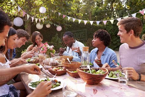 Friends Eating And Drinking Around Table At Outdoor Party Stock Photo