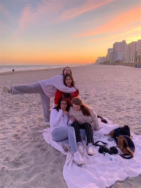 Three Women Are Sitting On A Blanket At The Beach