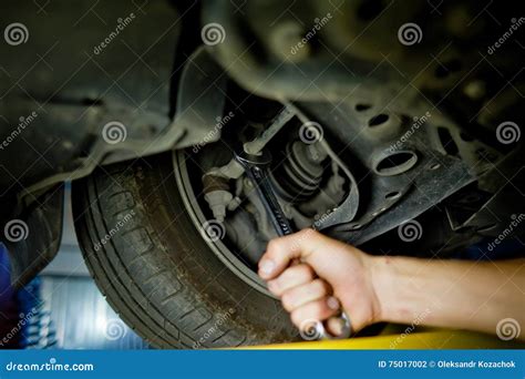 Element Of Auto Mechanic Working Underneath A Lifted Car Stock Photo
