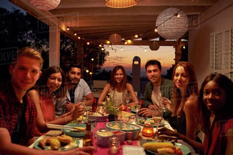 We strongly encourage our guests to embrace the convivial style of eating we, ourselves, enjoy! Friends at a dinner party on a patio looking to camera ...
