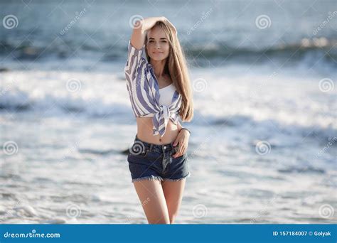 A Beautiful Young Woman With Long Straight Hair Sits Alone On Stones By The Sea Stock Image