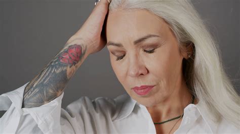 Closeup Portrait Of Attractive Mature Woman With Arm Tattoo And Blowing