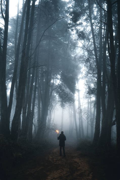 一个穿着罩衣的男人在黑暗的森林里举行仪式 包图企业站