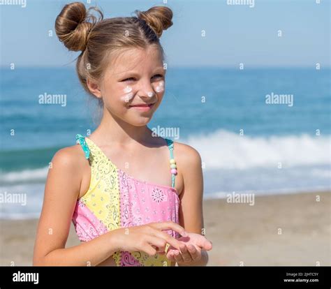 A Young Girl Applies Sunscreen To Her Body On The Beach Skin Care