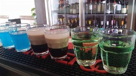 Four Glasses Filled With Different Colored Liquids On A Table Next To A