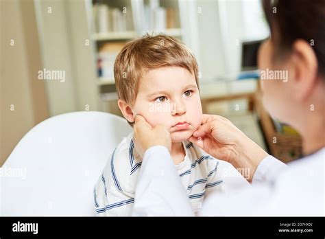 Pediatrician Palms The Tonsils And Swollen Lymph Nodes In A Child With