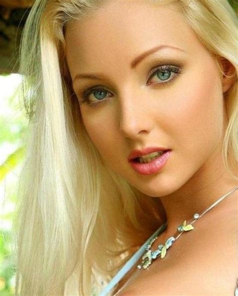 A Beautiful Blond Woman With Blue Eyes Posing For A Photo In Front Of
