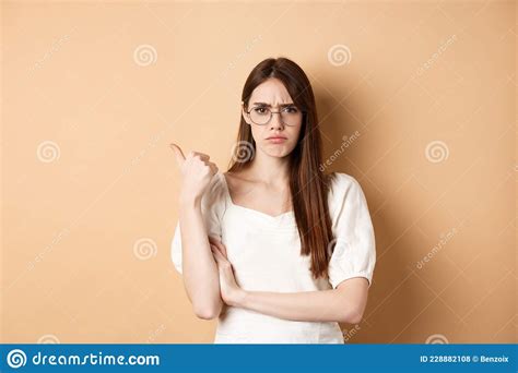 Disappointed Girl In Glasses Frowning Pointing Aside At Bad Product