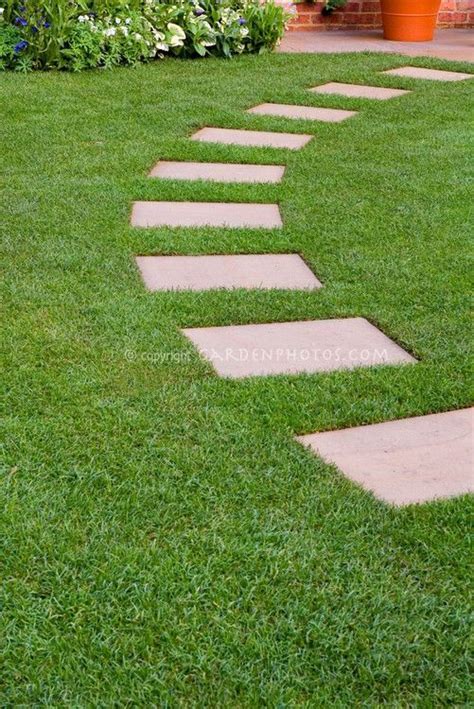 Stepping Stones In Perfect Lawn Grass Leading In An Arc To Backyard Patio With Perennial