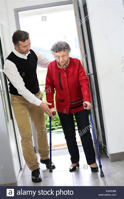 Man Helping Elderly Woman With Crutches Stock Photo Alamy