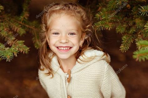 Adorable Little Curly Blond Girl In Beige Knitted Sweater Smiles Stock