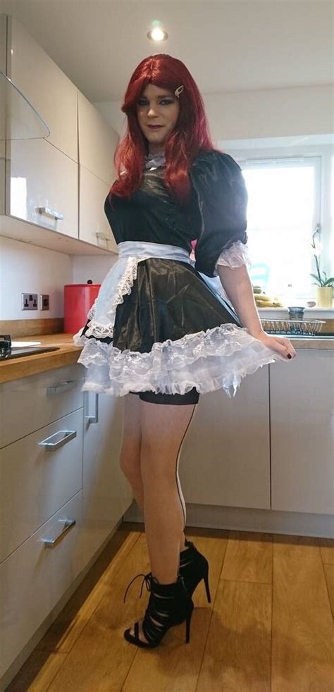A Woman With Red Hair Wearing A Black And White Dress Standing In The Middle Of A Kitchen
