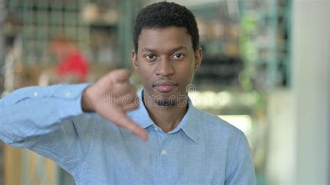 Portrait Of Disappointed Young African Man Doing Thumbs Down Stock