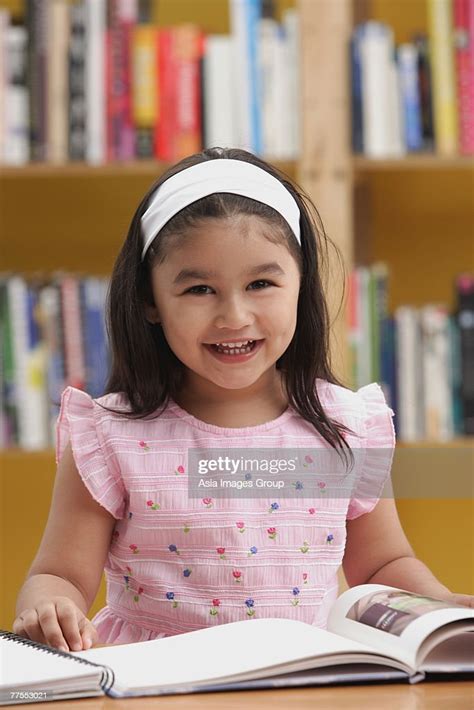 Young Girl Reading A Book Smiling At Camera High Res Stock Photo