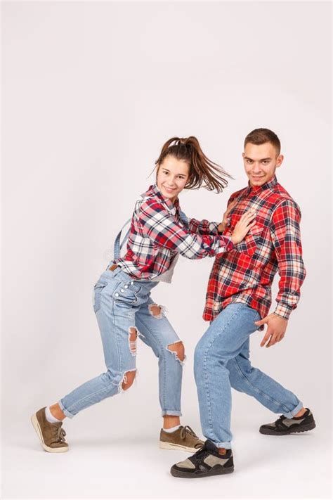 A Young Couple In Love In Jeans And In Checkered Shirts The Girl Pushes The Guy Stock Image