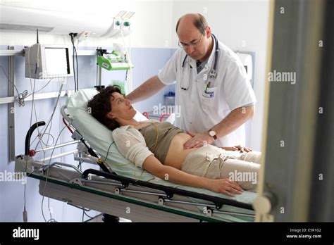 Hospital Doctor Examining The Abdomen Of A Patient By Palpation At