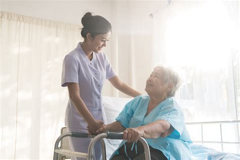 Asian Young Nurse Supporting Elderly Patient Disabled Woman In Using