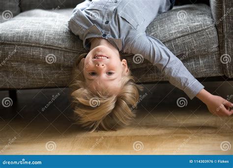 Kid Boy Lying Upside Down On Sofa Looking At Camera Stock Photo Image