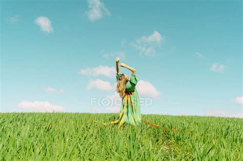 Young Woman Wearing A Green Dress Bending Over Backwards In A Field