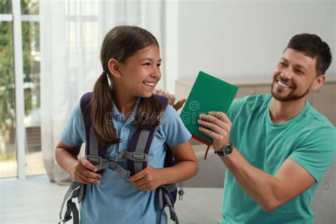 Padre Ayudando A Su Hija A Prepararse Para La Escuela En Casa Imagen De