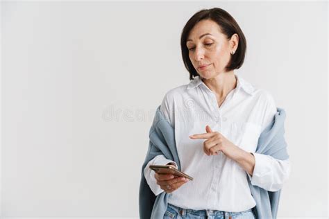 European Mature Woman Using And Pointing Finger At Mobile Phone Stock