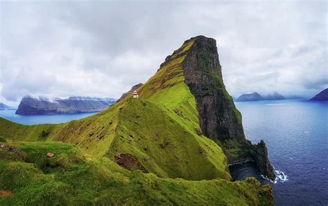 The faroe islands… through the eyes of a new yorker. Small lighthouse located near huge cliffs on island of ...