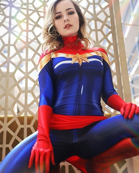 A Woman Dressed As Captain Marvel Sitting On A Bench In Front Of A
