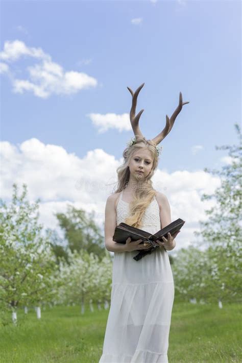 Teen Blonde Girl Wearing White Dress With Deer Horns On Her Head Stock
