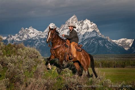 Wrangler And Horse Climbing A Steep Hill In Front Of The Grand Teton