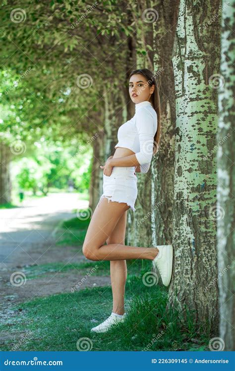 Portrait Of A Young Beautiful Brunette Woman In White Denim Shorts