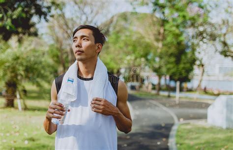 Sports Man Drinking Water After Exercising On Background Public Park