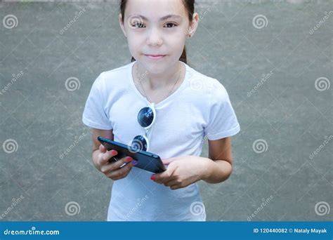 Cute Smiling Girl In White T Shirt With A Mobile Gadget In Hands Stock