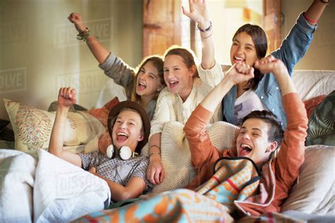 Group of teenagers having fun while watching tv on sofa - Stock Photo 
