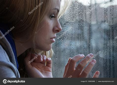 Sad Young Woman Looking Through Window On Rainy Day Stock Photo By