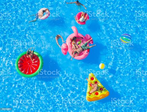 Aerial Cheerful Young Friends Having A Watergun Fight On Floaties At